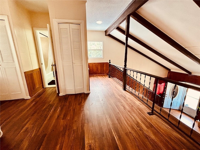 additional living space with a textured ceiling, vaulted ceiling with beams, dark hardwood / wood-style floors, and wood walls