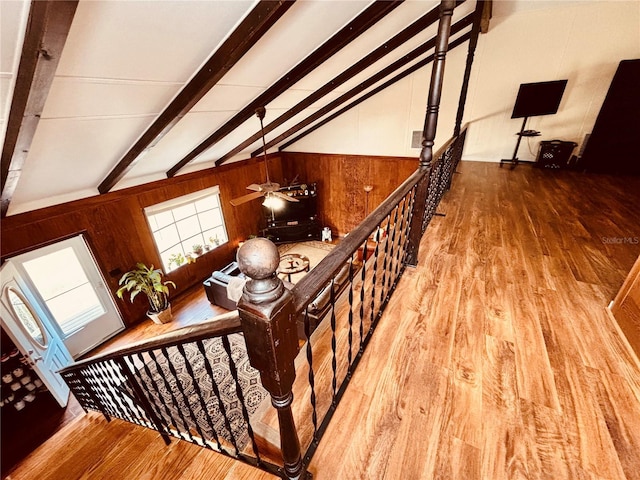 stairway featuring hardwood / wood-style floors, vaulted ceiling with beams, ceiling fan, and wood walls