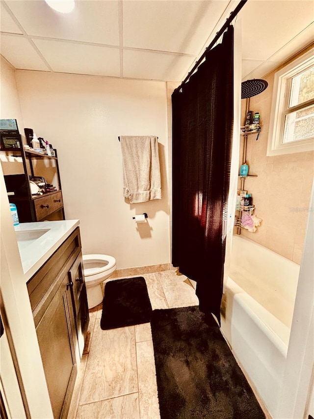 full bathroom featuring vanity, shower / bath combination with curtain, a paneled ceiling, and toilet