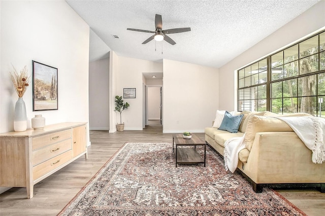 living room featuring hardwood / wood-style floors, a textured ceiling, ceiling fan, and lofted ceiling