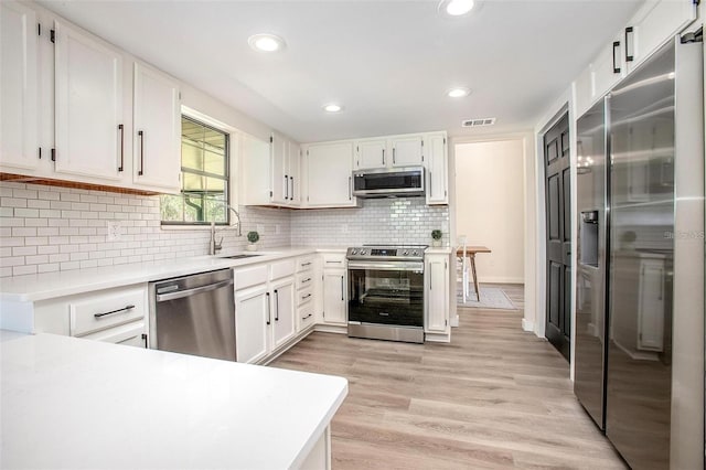 kitchen featuring sink, white cabinets, stainless steel appliances, and light hardwood / wood-style floors