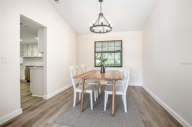 dining room featuring a chandelier, light hardwood / wood-style floors, and a textured ceiling