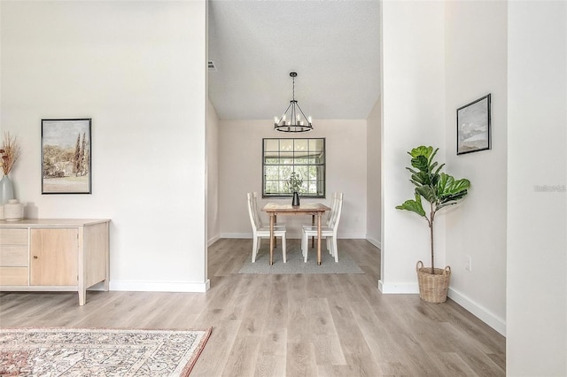 unfurnished dining area with an inviting chandelier, a textured ceiling, and light hardwood / wood-style flooring