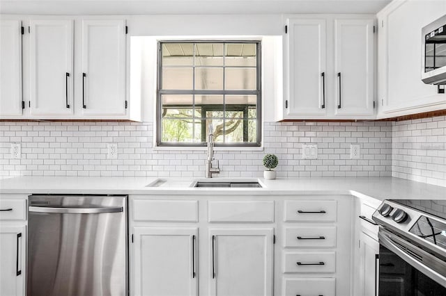 kitchen with decorative backsplash, sink, white cabinets, and stainless steel appliances