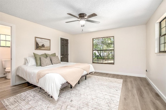 bedroom with ceiling fan, a textured ceiling, connected bathroom, and light hardwood / wood-style flooring