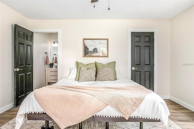 bedroom with hardwood / wood-style floors, ceiling fan, and a textured ceiling