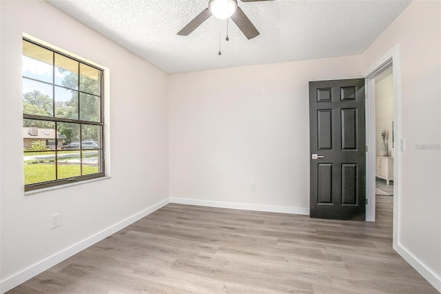 spare room with a textured ceiling, light hardwood / wood-style floors, and ceiling fan