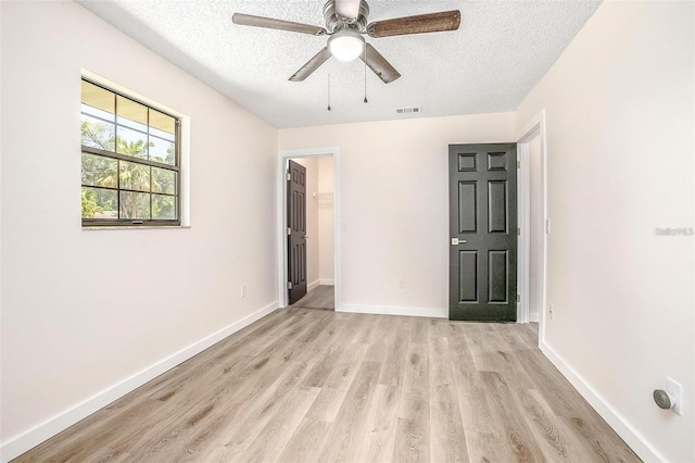 unfurnished room with ceiling fan, light wood-type flooring, and a textured ceiling