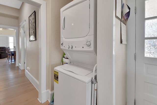 washroom featuring ceiling fan, stacked washing maching and dryer, and light wood-type flooring