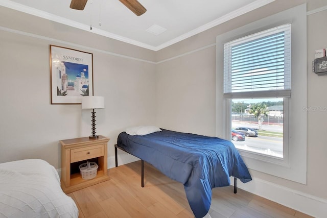 bedroom featuring hardwood / wood-style floors, ceiling fan, crown molding, and multiple windows