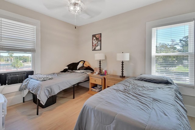 bedroom with ceiling fan, cooling unit, and wood-type flooring