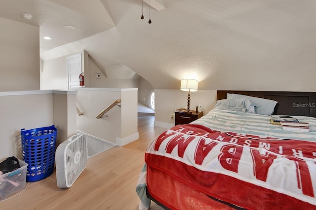 bedroom featuring a textured ceiling, lofted ceiling, and light wood-type flooring