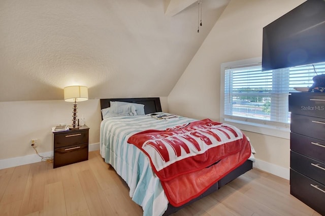 bedroom featuring light hardwood / wood-style floors, lofted ceiling, and a textured ceiling