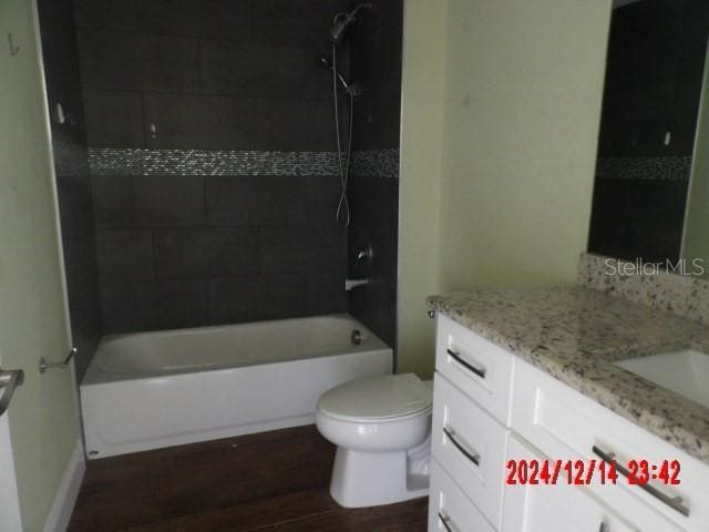 full bathroom with toilet, hardwood / wood-style floors, vanity, and tiled shower / bath