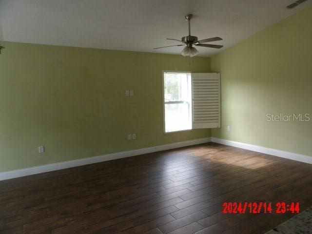 empty room with dark hardwood / wood-style floors and ceiling fan