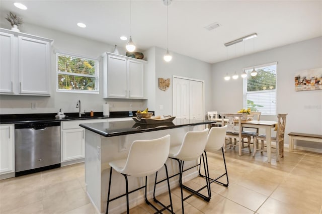 kitchen with plenty of natural light, white cabinets, stainless steel dishwasher, and decorative light fixtures