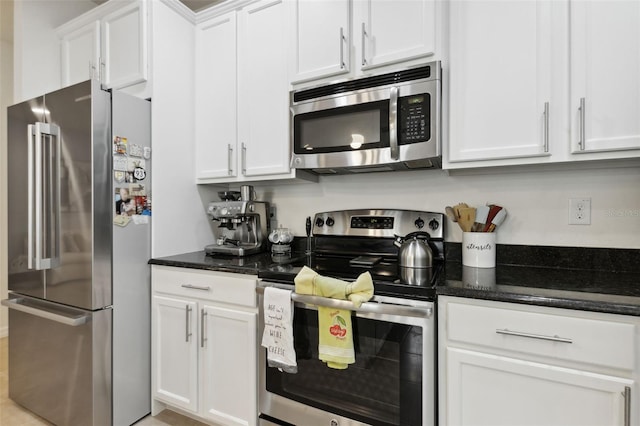 kitchen with stainless steel appliances, white cabinetry, and dark stone counters