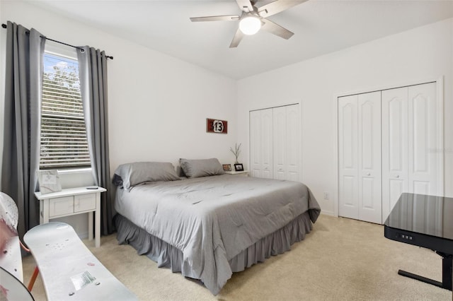 carpeted bedroom featuring ceiling fan and multiple closets