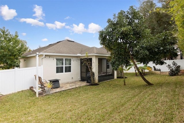 back of property featuring a sunroom, a patio area, and a lawn