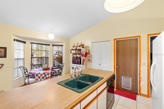 kitchen with dishwasher, light tile patterned floors, white refrigerator, sink, and lofted ceiling