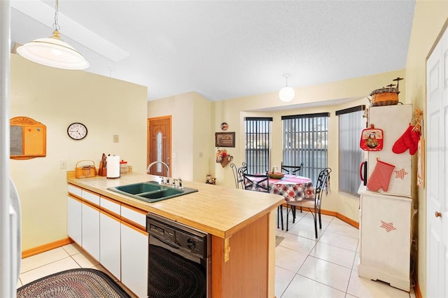 kitchen featuring white fridge, hanging light fixtures, sink, white cabinetry, and light tile patterned flooring