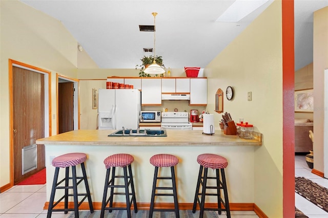 kitchen with white appliances, white cabinets, lofted ceiling with skylight, and a breakfast bar