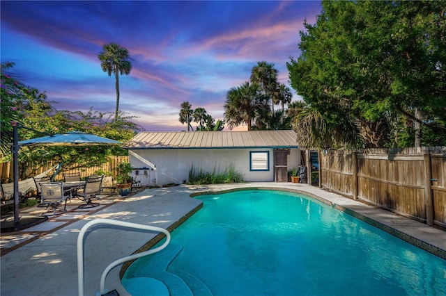 pool at dusk featuring a patio area