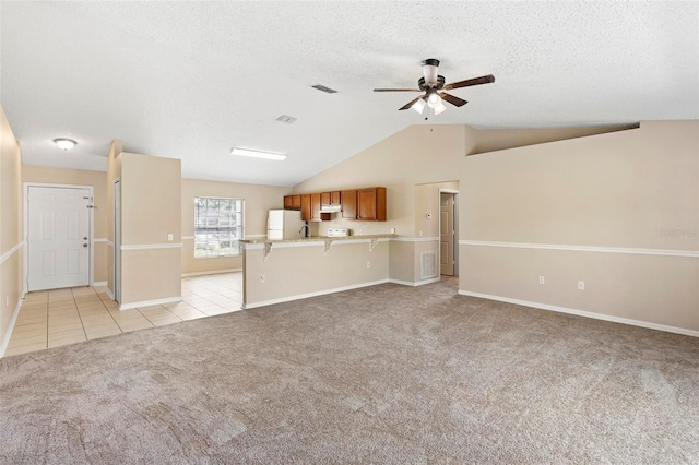 unfurnished living room featuring ceiling fan, light colored carpet, lofted ceiling, and a textured ceiling