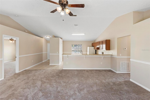 unfurnished living room with a textured ceiling, light colored carpet, ceiling fan, and lofted ceiling