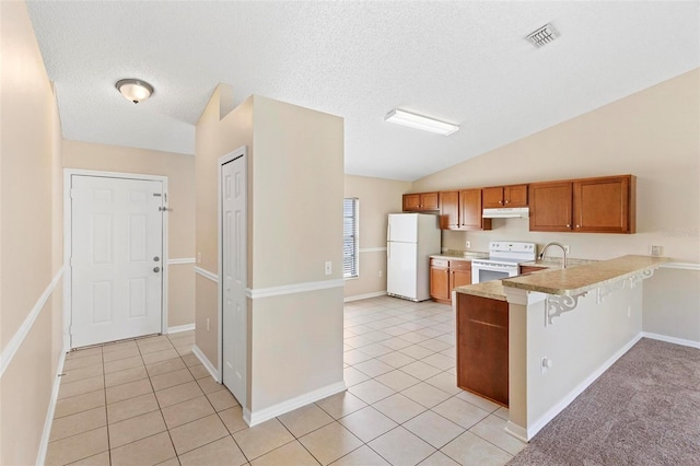 kitchen with a kitchen breakfast bar, kitchen peninsula, lofted ceiling, a textured ceiling, and white appliances