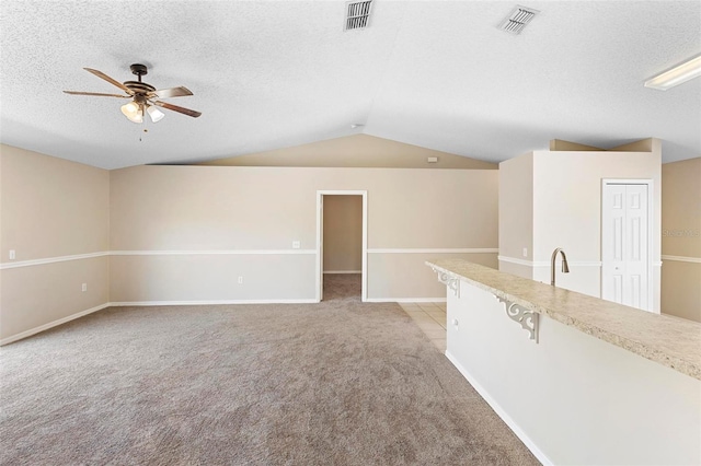 unfurnished living room featuring light carpet, sink, vaulted ceiling, ceiling fan, and a textured ceiling