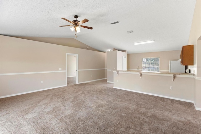 unfurnished living room with ceiling fan, light colored carpet, lofted ceiling, and a textured ceiling