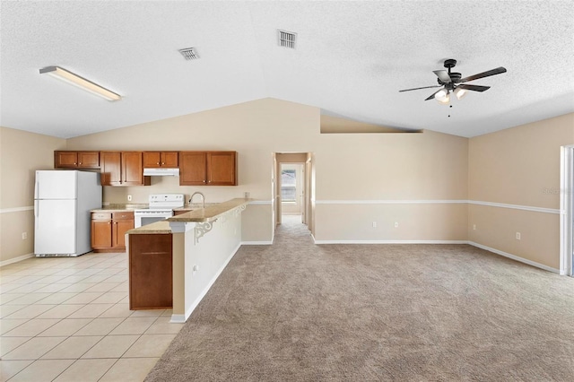 kitchen featuring ceiling fan, a kitchen breakfast bar, kitchen peninsula, lofted ceiling, and white appliances