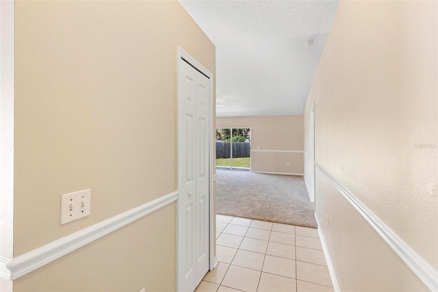 corridor with light colored carpet and a textured ceiling