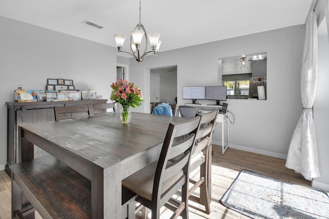 dining room with light hardwood / wood-style floors and a chandelier