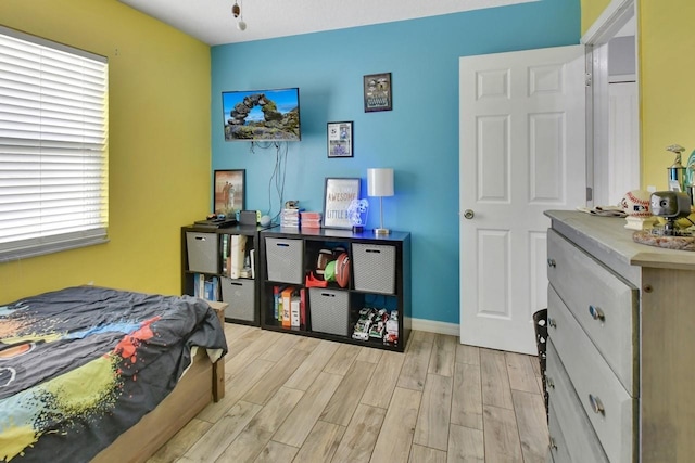 bedroom with light hardwood / wood-style floors and multiple windows