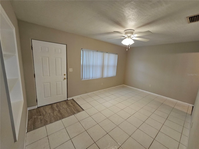 foyer entrance with a textured ceiling, ceiling fan, and light tile patterned flooring