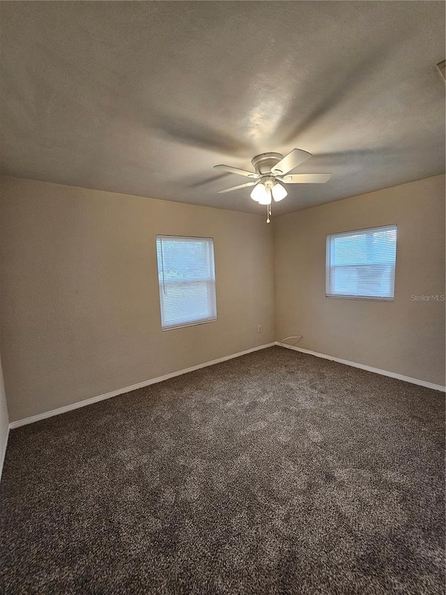 empty room with ceiling fan, dark carpet, and a textured ceiling