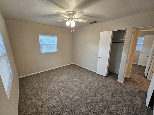 unfurnished bedroom with dark colored carpet, ceiling fan, and a closet