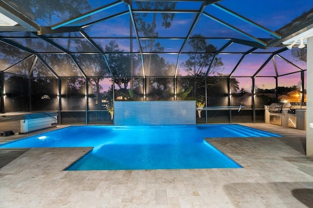 pool at dusk with a patio area, a lanai, exterior kitchen, and a hot tub