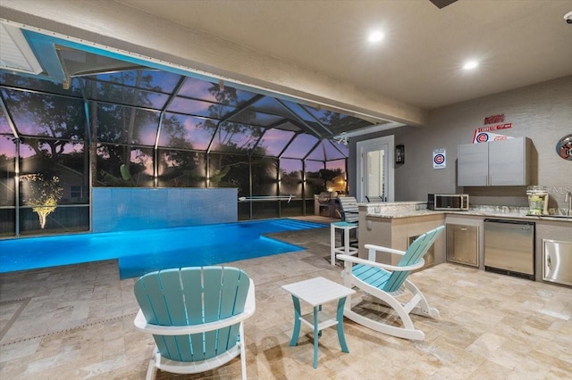 pool at dusk with a patio, area for grilling, a lanai, and sink