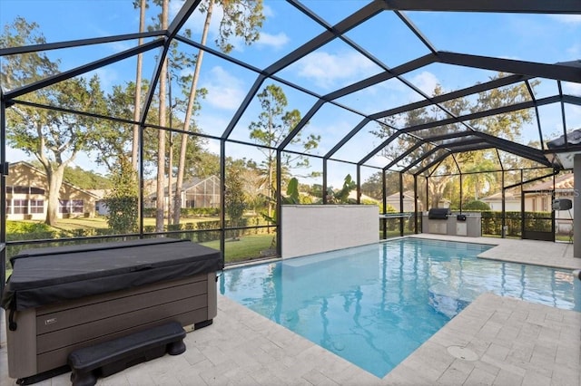 view of swimming pool featuring glass enclosure, a patio area, and exterior kitchen