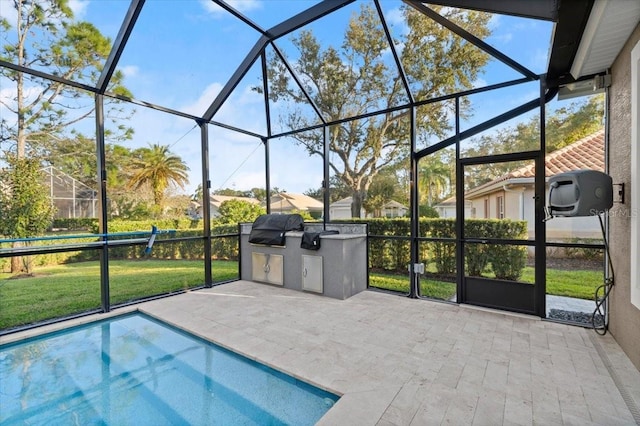 view of swimming pool with exterior kitchen, glass enclosure, grilling area, a patio area, and a yard