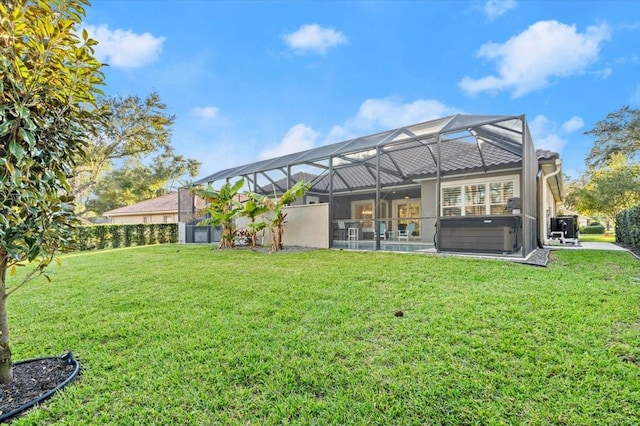 rear view of property featuring glass enclosure, a yard, and a hot tub