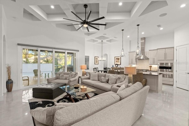 living room featuring beamed ceiling, coffered ceiling, ceiling fan with notable chandelier, and a high ceiling