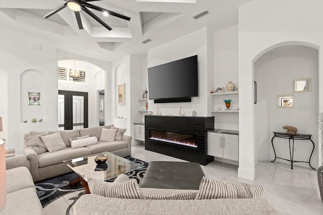 living room with a high ceiling, ceiling fan, coffered ceiling, and beam ceiling