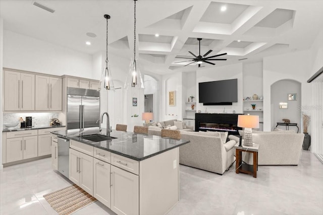 kitchen featuring a kitchen island with sink, a towering ceiling, sink, and appliances with stainless steel finishes