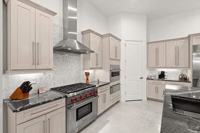 kitchen with tasteful backsplash, high quality appliances, dark stone counters, and wall chimney range hood