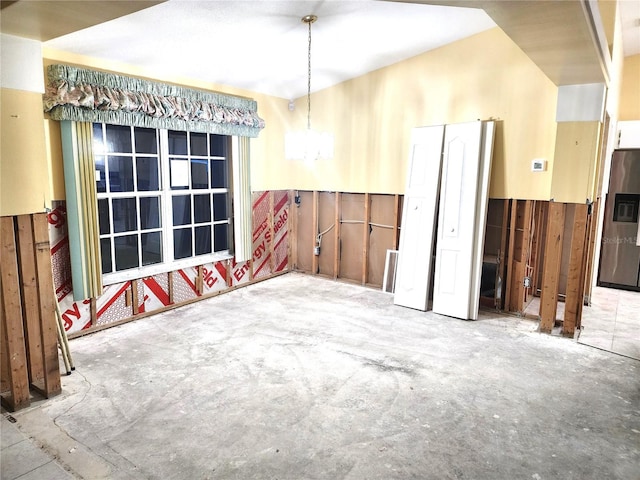 unfurnished room with concrete floors and a chandelier