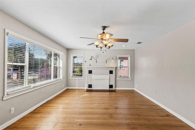 unfurnished living room featuring light hardwood / wood-style floors, a brick fireplace, and ceiling fan